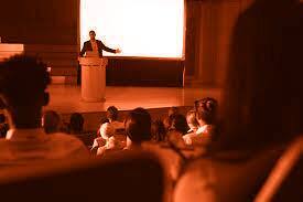 An image showing an audience listening to a speaker